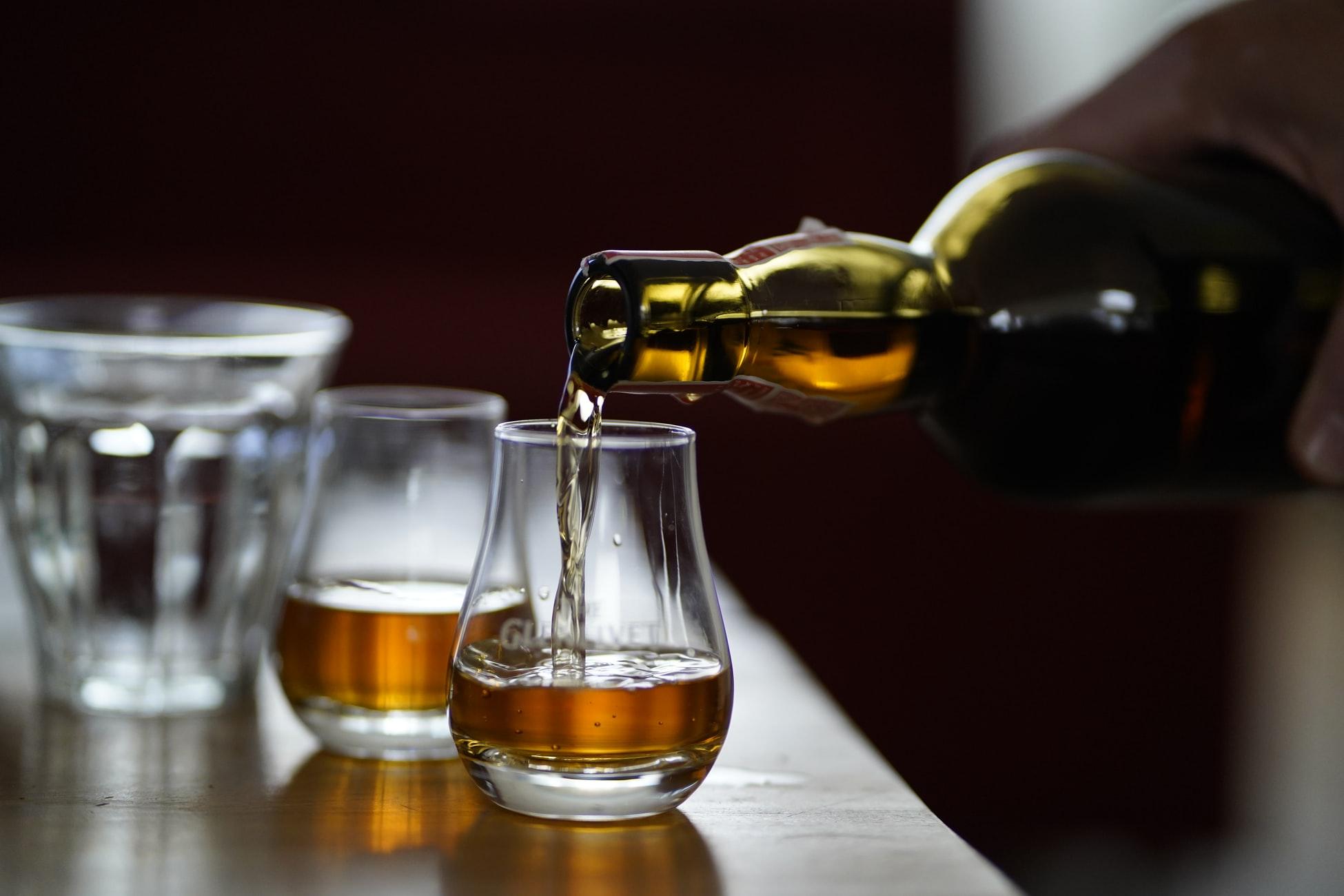 nalievanie whisky do pohárika z fľaše